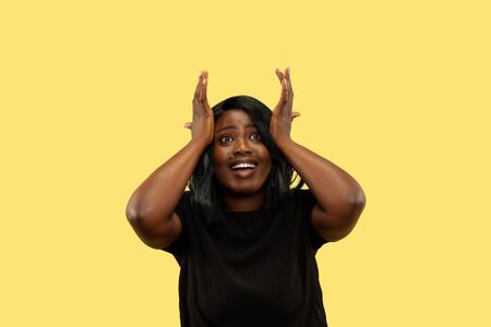Young african-american woman isolated on yellow studio background, facial expression. Beautiful...
