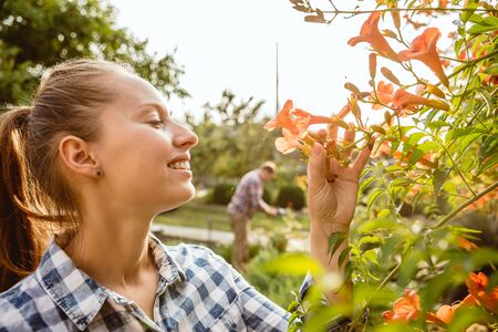 Young and happy farmers couple at their garden in sunny day. Man and woman engaged in the cultivation of eco friendly products. Concept of farming, agriculture, healthy lifestyle, family occupation.の写真素材