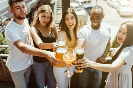 Young group of friends drinking beer, having fun, laughting and celebrating together. Women and men...
