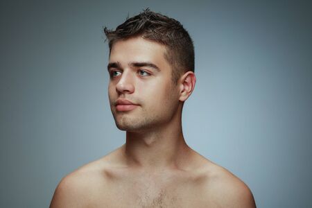 Portrait of shirtless young man isolated on grey studio background. Caucasian healthy male model looking at side and posing. Concept of mens health and beauty, self-care, body and skin care.の写真素材