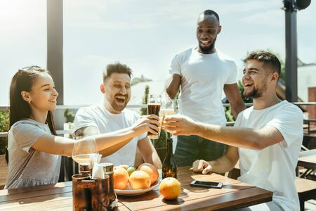 Young group of friends drinking beer, having fun, laughting and celebrating together. Women and men...