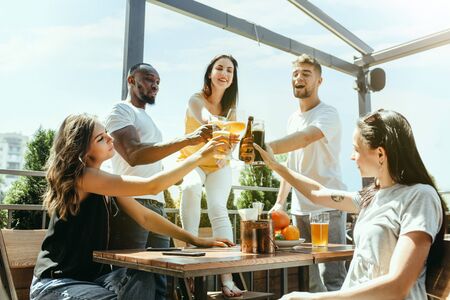 Young group of friends drinking beer, having fun, laughting and celebrating together. Women and men...