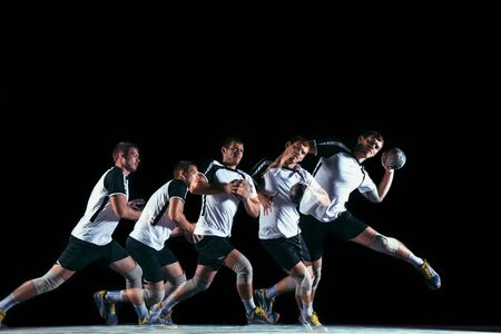Caucasian young handball player in action and motion in mixed and strobe light on black studio background. Fit professional sportsman. Concept of sport, movement, energy, dynamic, healthy lifestyle.の写真素材
