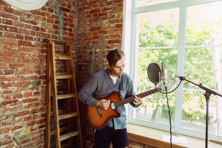 Young man recording music video blog, home lesson or song, playing guitar or making broadcast...
