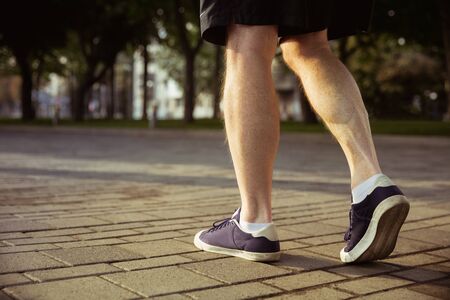 Senior man as runner at the citys street. Close up shot of legs in sneakers. Caucasian male model jogging and cardio training in summers morning. Healthy lifestyle, sport, activity concept.の写真素材