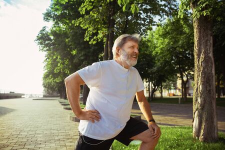 Senior man as runner at the citys street. Caucasian male model jogging and cardio training in...