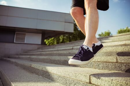 Senior man as runner at the citys street. Close up of legs in sneakers. Caucasian male model jogging...