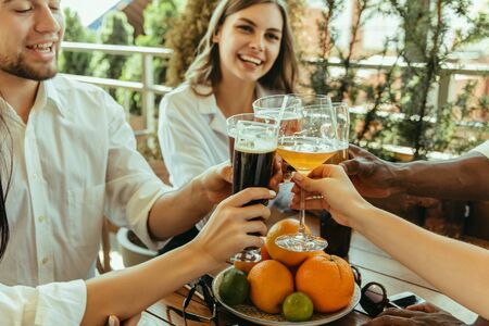 Young group of friends drinking beer, having fun, laughting and celebrating together. Women and men with beers glasses in sunny day. Oktoberfest, friendship, togetherness, happiness, summer concept.の写真素材