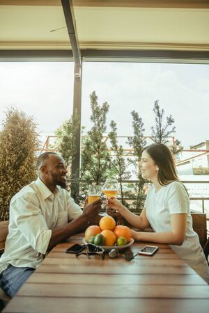 Young friends or couple drinking beer, having fun, laughting and celebrating together. Woman and man with beers glasses in sunny day. Oktoberfest, friendship, togetherness, happiness, summer concept.の写真素材