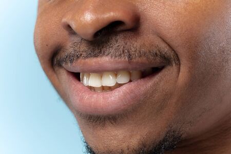 Close up portrait of young african-american man on blue background. Human emotions, facial...