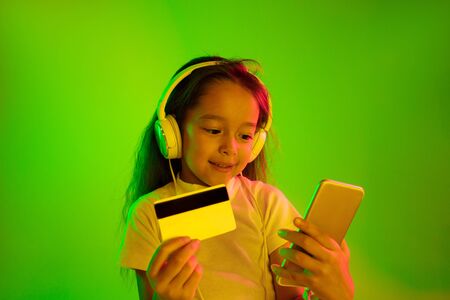 Beautiful female half-length portrait isolated on green backgroud in neon light. Young emotional...