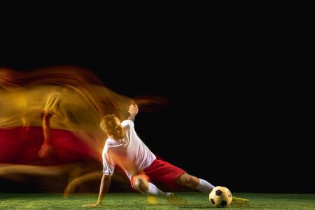 Flexible. Young caucasian male football or soccer player in sportwear and boots kicking ball for the...