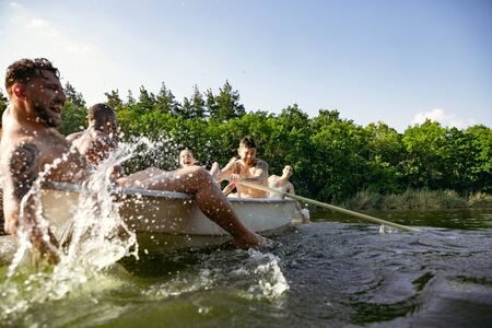 Happy group of friends having fun while laughting and swimming in river. Joyful men and women in...