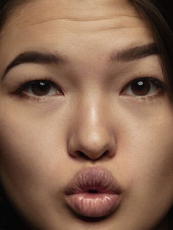 Close up portrait of young and emotional chinese woman. Highly detail photoshot of female model with well-kept skin and bright facial expression. Concept of human emotions. Sending kisses.の写真素材