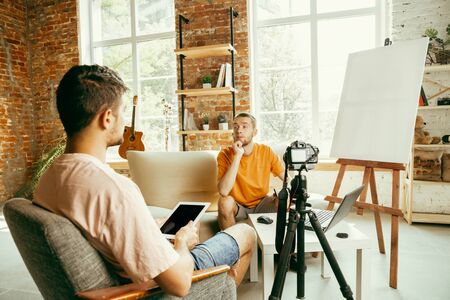 Two young caucasian male bloggers in casual clothes with professional equipment or camera recording...