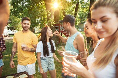 Group of happy friends having beer and barbecue party at sunny day. Resting together outdoor in a...