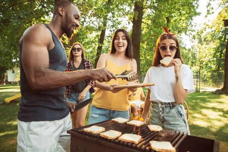 Group of happy friends having beer and barbecue party at sunny day. Resting together outdoor in a forest glade or backyard. Celebrating and relaxing, laughting. Summer lifestyle, friendship concept.の写真素材