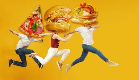 Fast food. Young caucasian people headed by pizzas slice and burgers or sandwiches running and jumping on orange background. Copyspace for your ad. Creative collage about nutrition.の写真素材