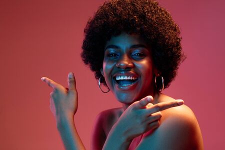 Flowers honey. Portrait of female fashion model in neon light on red gradient studio background....