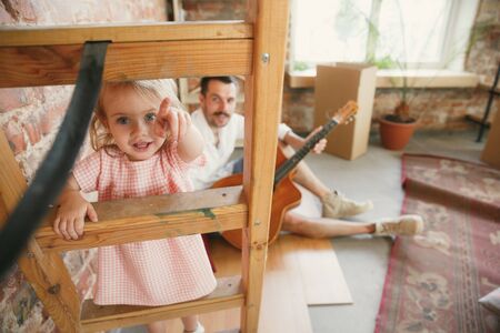New life. Young father and his daughter moved to a new house or apartment. Look happy and confident. Moving, relations, lifestyle concept. Playing together, preparing for repair and laughting.の写真素材