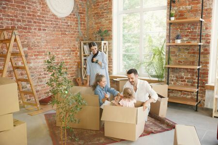 New life. Adult family moved to a new house or apartment. Spouses and children look happy and...