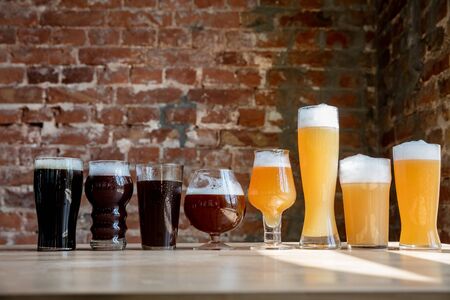 Glasses of dark and light beer and ale in sunlight on brick wall background. Cold delicious alcohol drinks are prepared for a big friend's party. Concept of holiday, fun, meeting, oktoberfest.の写真素材