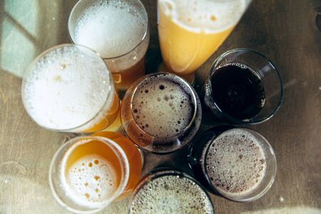 Top view of glasses of dark and light beer and ale on brick wall background. Cold delicious alcohol drinks are prepared for a big friend's party. Concept of holiday, fun, meeting, oktoberfest.の写真素材