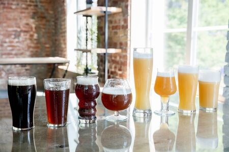 Glasses of dark and light beer and ale in sunlight on brick wall background. Cold delicious alcohol...
