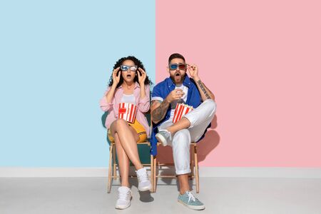 Young emotional caucasian couple in casual clothes posing on pink and blue background. Concept of...