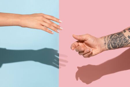 Closeup shot of human going to holding hands isolated on blue-pink studio background. Concept of human relations, friendship, partnership, family. Copyspace.の写真素材