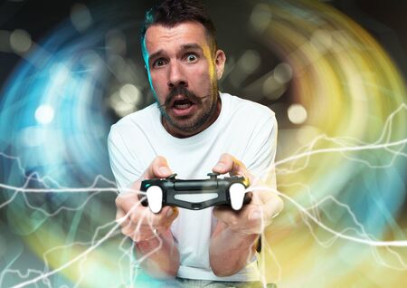 Enthusiastic gamer. Joyful young man holding a video game controller being full of emotions isolated...