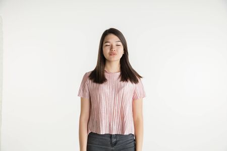 Beautiful female half-length portrait isolated on white studio background. Young emotional woman in casual clothes. Human emotions, facial expression concept. Dreaming with eyes closed.の写真素材