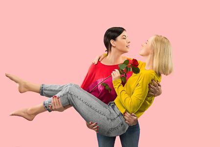 Such a big love. Pretty romantic couple in casual outfits isolated on coral studio background. Two...