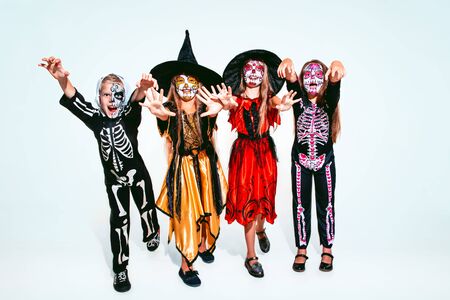 Kids or teens like witches and vampires with bones and glitter on white background. Caucasian models looks scary and playful. Halloween, black friday, sales, autumn holidays concept. The night of fear.の写真素材