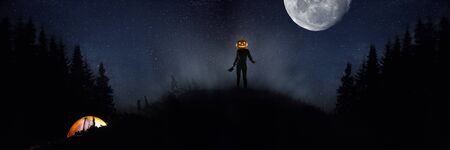 Halloween theme: scary maniac with pumpkin head in dark forest on sky background with midnight moon....