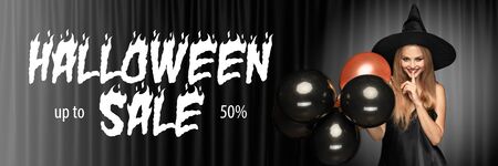 Young blonde woman in hat on scary black background. Attractive caucasian female model smiling. Halloween sales, black friday, cyber monday, autumn concept. Flyer for your ad. Holding balloons.の写真素材