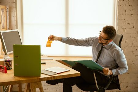 Deals. A young businessman working in the office, getting new work place. Young male office worker...