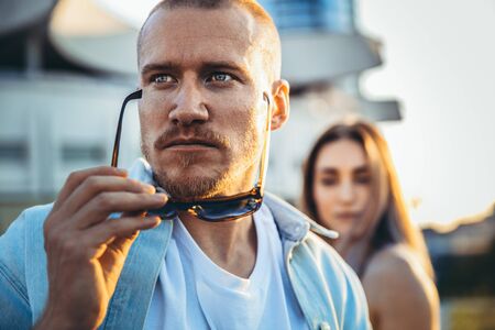 Tanned young caucasian couple, modern lovestory in film grain effect and vintage style. Sunset. Walking on the citys street, confident and serious, summer. Honeymoon concept. Toned in teal orange.の写真素材
