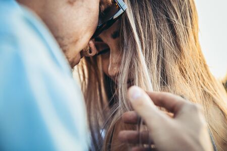 Tanned young caucasian couple, modern lovestory in film grain effect, vintage style. Sunset time. Close up of emotions and feelings, tender and happy, summer. Honeymoon concept. Toned in teal orange.の写真素材