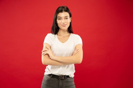 Caucasian young womans half-length portrait on red studio background. Beautiful female model in...