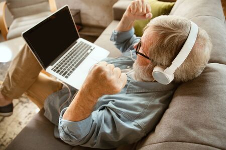 Senior man working with laptop at home - concept of home studying. Caucasian male model sitting on...