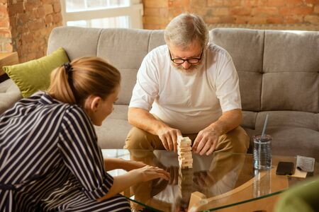 Senior man doing his wooden constructor at home - concept of home studying. Caucasian male model...