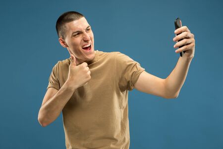 Caucasian young mans half-length portrait on blue studio background. Beautiful male model in shirt....