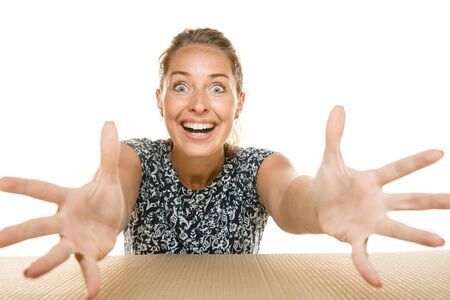 Young astonished woman opening the biggest postal package isolated on white. Shocked female model on...