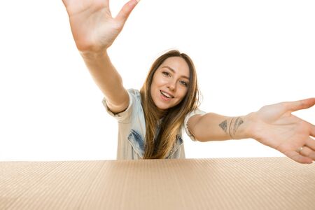 Young astonished woman opening the biggest postal package isolated on white. Shocked female model on...