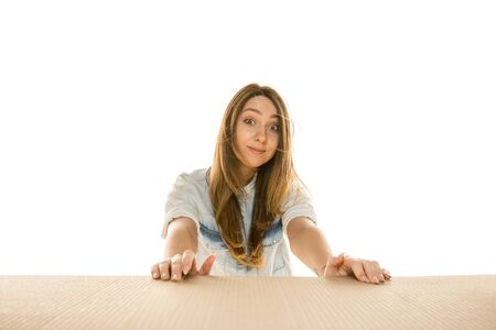 Young sad woman opening the biggest postal package isolated on white. Shocked upset female model on...