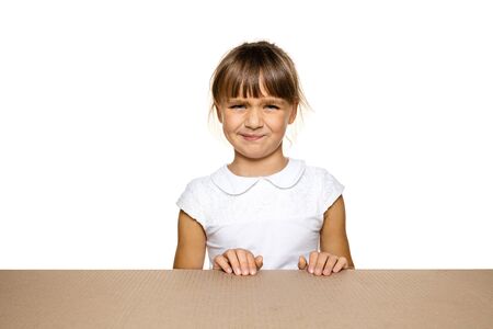 Cute and upset little girl opening the biggest postal package. Disappointed young female model on top of cardboard box looking inside. Gift, present, delivery, shipment, sales, black friday concept.の写真素材