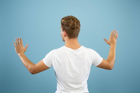 Caucasian young mans half-length portrait on blue studio background. Beautiful male model in shirt....