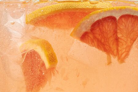 Close up view of the lemon and grapefruit slices in lemonade background. Texture of cooling sweet...