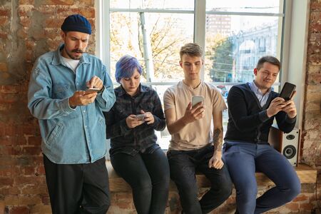 Group of happy caucasian young people standing behind the window. Sharing a news, photos or videos...